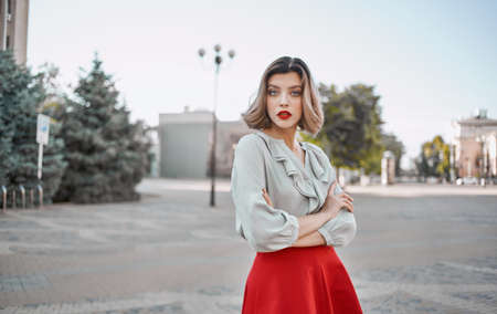 a woman in a shirt skirt strolls through the central streets of the city and tall buildings in the backgroundの写真素材