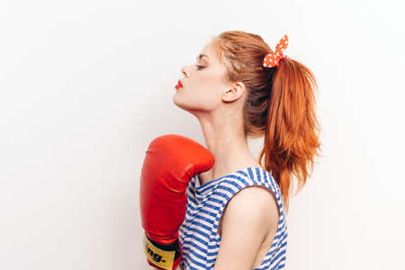 active woman boxing in red gloves and a striped t-shirt on a light backgroundの写真素材