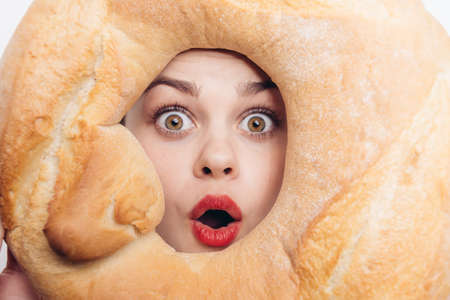 happy woman with round loaf of bread in front of face bright makeup emotions funの写真素材