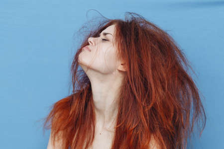 red-haired woman with tangled hair on her head on blue background cropped viewの写真素材