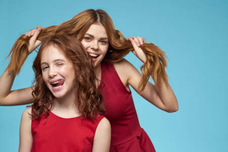 Mom and daughter in red dresses entertainment lifestyle fun studio blue backgroundの写真素材