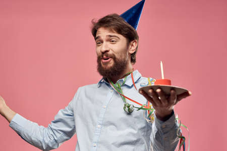 Bearded man with cake on pink background birthday party corporate emotions model lonelinessの写真素材