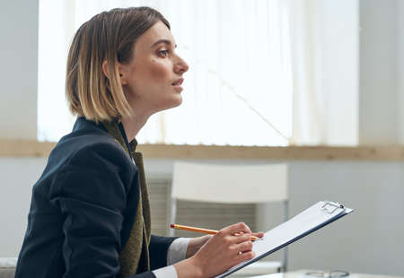 Side view of a business woman with documents sits indoorsの写真素材