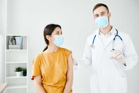 professional doctor holds a syringe in his hand and a female patient vaccinationの写真素材