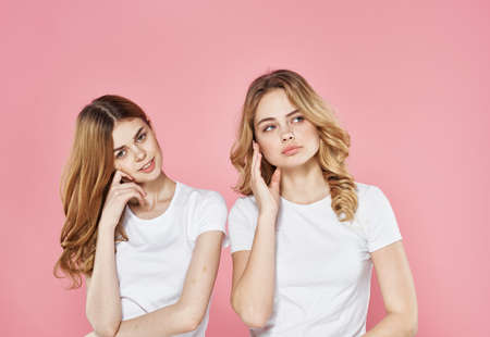 Two girlfriends in white t-shirts tired look vacation lifestyle pink backgroundの写真素材