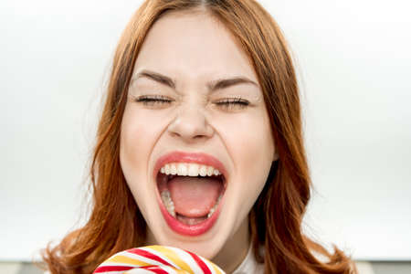 emotional woman with open mouth big multicolored lollipop