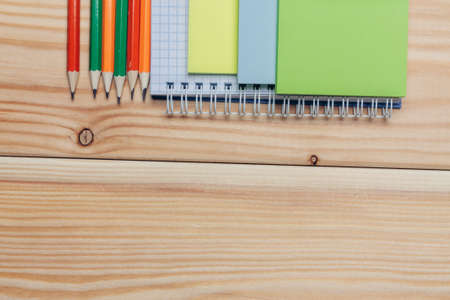 multicolored pencils notepads stationery wooden table top view. High quality photoの写真素材