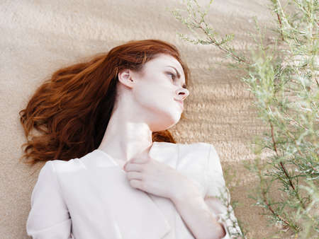 Pretty red-haired woman lies on the sand vacation tan travelの写真素材