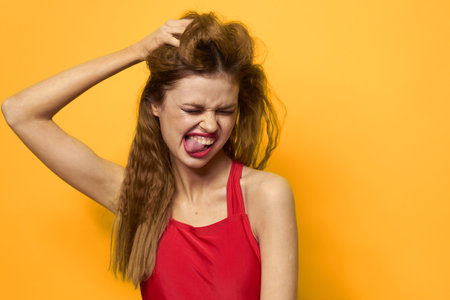 Pretty woman wavy hair red tank top fashion lifestyle cosmetics yellow backgroundの写真素材