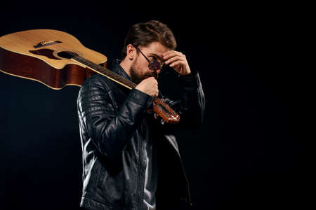A man with a guitar in his hands leather jacket music performance rock star modern style dark backgroundの写真素材