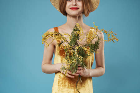 Elegant woman golden dress bouquet of mimosa holiday blue backgroundの写真素材