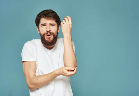 brunet man gesturing with his hands in a white t-shirt on a blue backgroundの写真素材