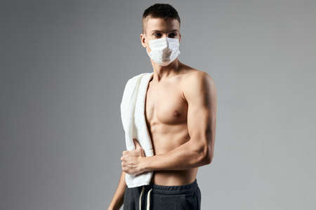 sport guy with towel on shoulders medical mask posing workoutの写真素材