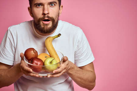 bearded man wearing white t-shirt fruit diet food health pink backgroundの写真素材