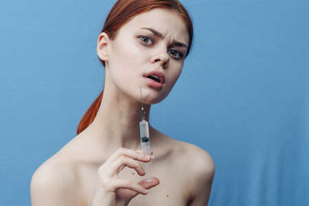 syringe in woman hand on blue background injection rejuvenation botox cropped viewの写真素材