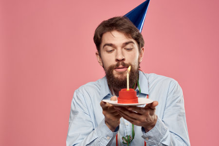Birthday of a man with a cake and with a candle on a pink backgroundの写真素材