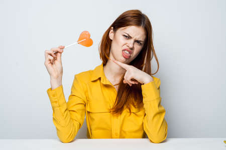 emotional woman with lollipop in her hands yellow yellow shirt isolated backgroundの写真素材