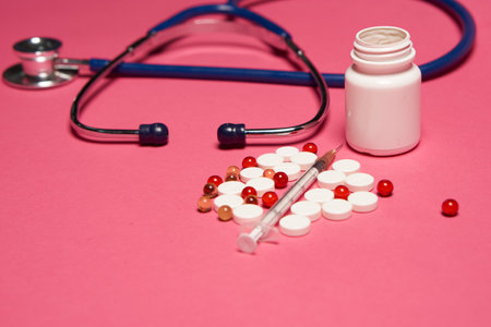 Pills white jar stethoscope health syringe pink background cropped viewの写真素材