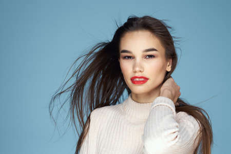 Brunette in a white sweater red lips charm long hair blue backgroundの写真素材