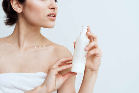 Pretty brunette with bare shoulders lotion in hands skin care close-upの写真素材