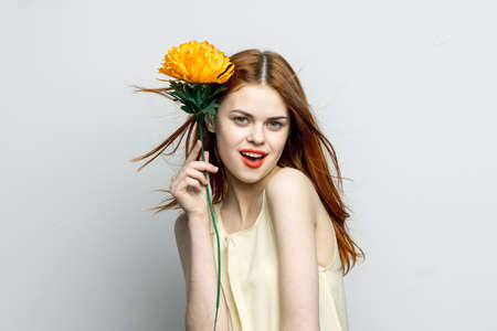 smiling woman red lips yellow flower in hands of charm gift modelの写真素材
