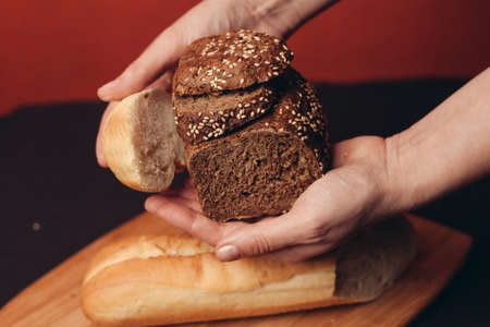 flour products in female hands and sliced baguette on a boardの写真素材