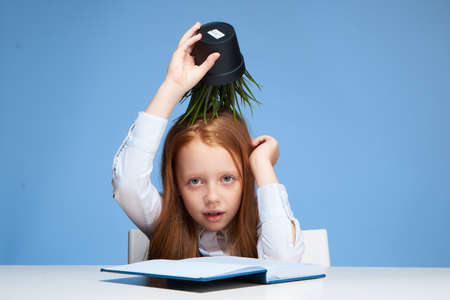 schoolgirl turned pretend sitting at the table and doing learning lessonsの写真素材