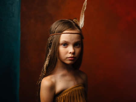 The girl on a red background with an ornament on the head of a featherの写真素材