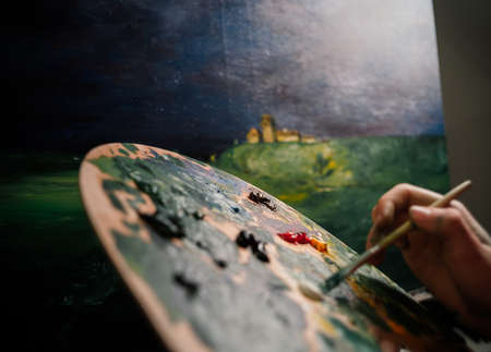 woman paints a picture with paints artist easel palette Bright colorsの写真素材