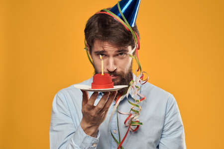 A man holding a cake in a plate and a candle from above isolated backgroundの写真素材