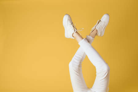 Womens legs white pants and sneakers fashion studio elegant styleの写真素材