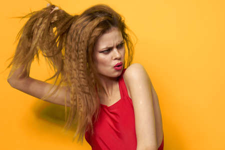 Pretty woman wavy hair red tank top fashion lifestyle cosmetics yellow backgroundの写真素材