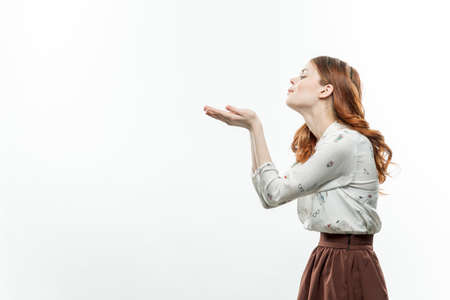 cheerful red-haired woman holding hands in front of her lifestyle Copy Space light backgroundの写真素材