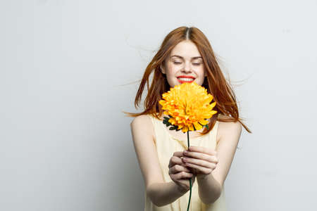 cheerful pretty woman with a big yellow flower in her hands emotions red lips fun charmの写真素材