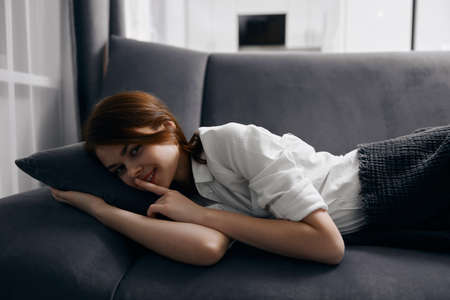 woman in white t-shirt lies on gray sofa cropped viewの写真素材