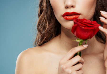 Romantic woman with red rose bared shoulders and blue background brunetteの写真素材