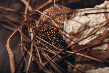 Loaf of Bread In a paper package lies on branches in a nest on a wooden tableの写真素材