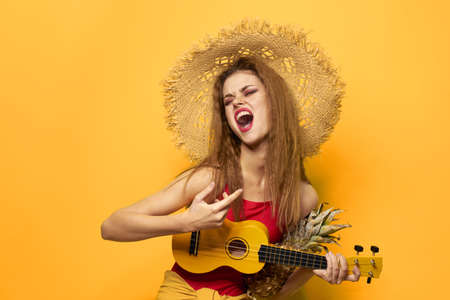Woman holding Ukulele straw hat lifestyle Exotic yellow backgroundの写真素材