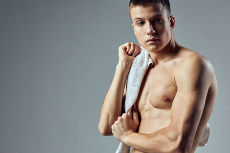 sporty man with towel on shoulders cropped view gray workout background