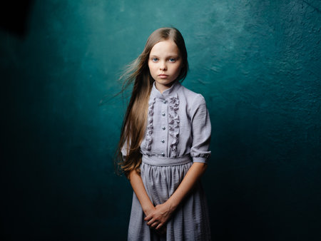 Charming girl with loose hair on a turquoise background in a gray dressの写真素材