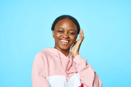 woman of african appearance in a pink sweater on a blue backgroundの写真素材