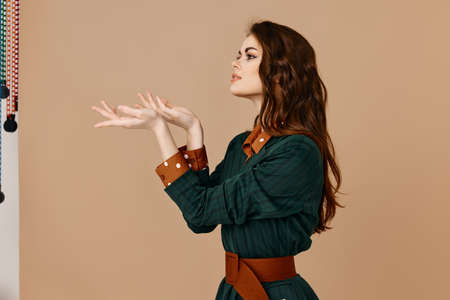 pretty brunette in a suit belt at the waist and gesturing with her hands beige backgroundの写真素材
