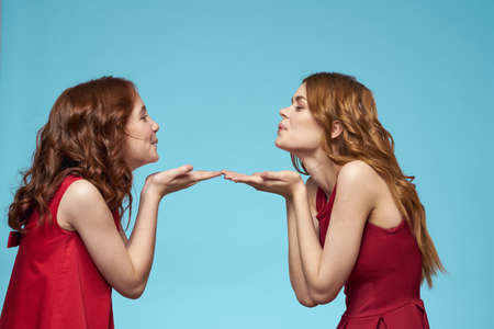 Family mom and daughter hug red dresses communication emotions blue backgroundの写真素材