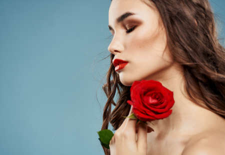 Sexy woman with red rose and blue background with brunette curlsの写真素材