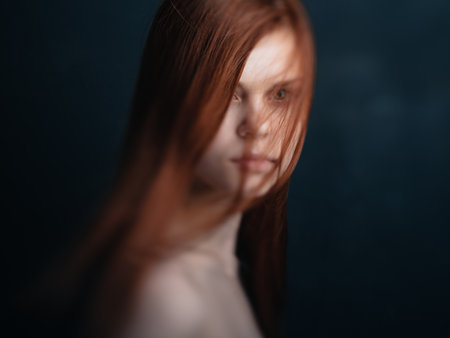 Portrait of a charming woman red hair bared shoulders close-up black backgroundの写真素材