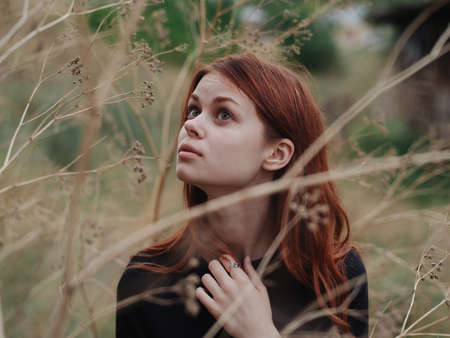 Woman near dry branches of trees on nature in autumn in the forestの写真素材