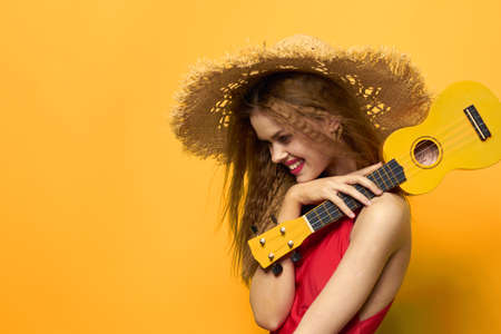 Woman holding Ukulele straw hat lifestyle Exotic yellow backgroundの写真素材