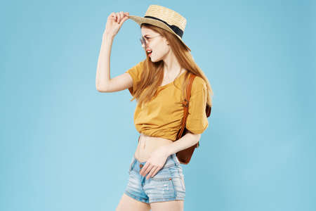 Beautiful elegant woman in hat fashion clothes backpack studio blue backgroundの写真素材