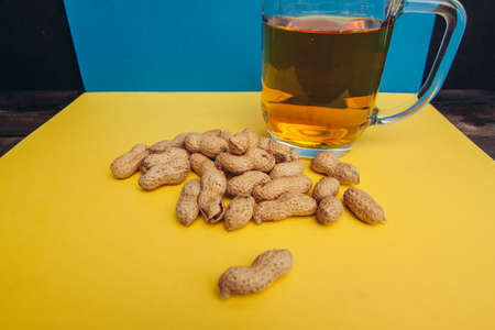 peanuts in shells beer mug snack alcohol yellow backgroundの写真素材