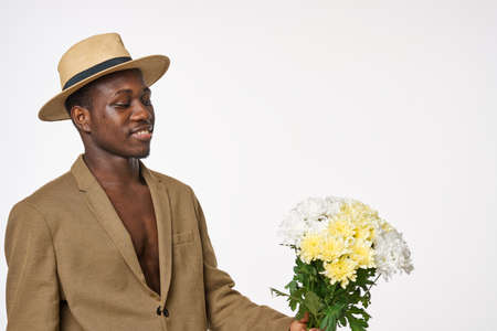 guy of african appearance with a bouquet of flowers and a hatの写真素材